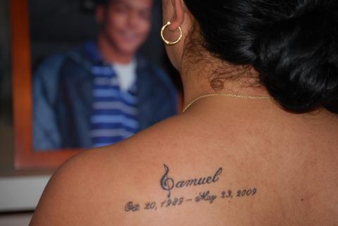 Isaida's back tattoo in memory of her son, Samuel. In the background is a framed photo of a smiling Samuel.