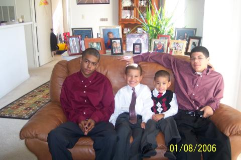 Isaida's four sons seated on a couch looking at the camera.
