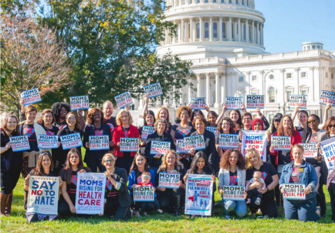 A diverse group of women holding signs in front of the US Capitol