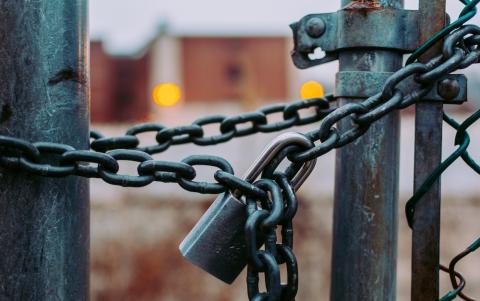 Chained gate with building in background. Photo by Jose Fontano on Unsplash.