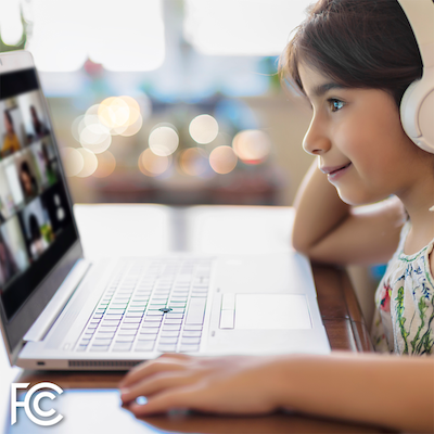 Girl with headphones looking at a computer (source: FCC)