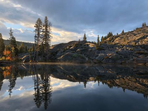 [IMAGE DESCRIPTION: A nature landscape photo featuring pines, granite outcroppings, and a serene pond reflecting the scenery.]