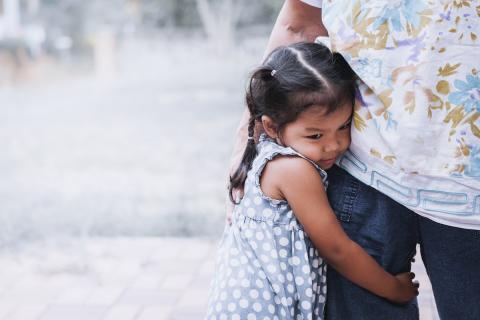 [IMAGE DESCRIPTION: A photo of a young child looking down and hugging an adult's leg.]