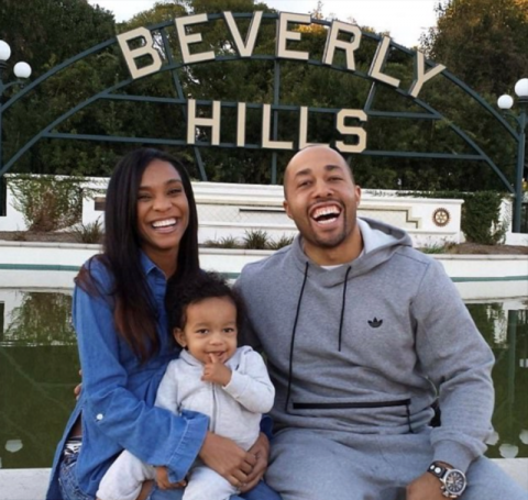  A couple with a toddler smiles at the camera. They are sitting outside.]