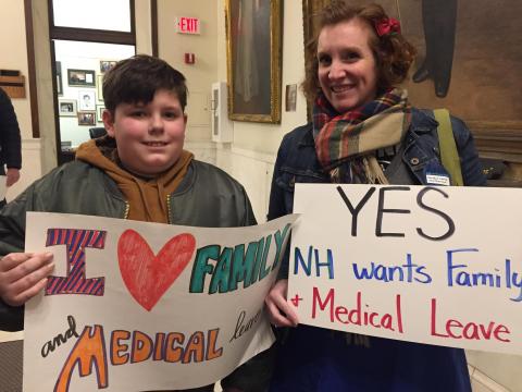 [IMAGE DESCRIPTION: Mother and son look at camera, smiling, holding sign for paid family and medical leave in New Hampshire.]