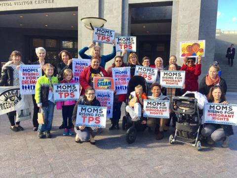 MomsRising supporters hold signs to show support for immigrant families' rights.