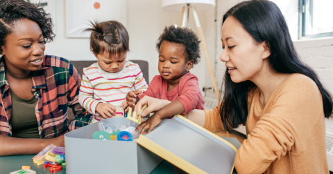 Two children and two adults playing with toys in a box