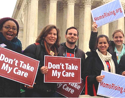 A group of people hold "Don't Take My Care" signs standing in front of the U.S. Supreme Court