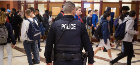 School Resource Officer (SRO) watching students in a High School hallway