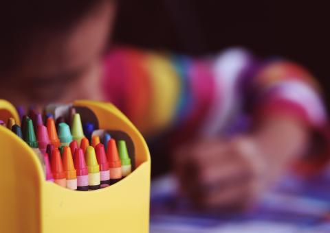 photo of child coloring with crayons in the foreground