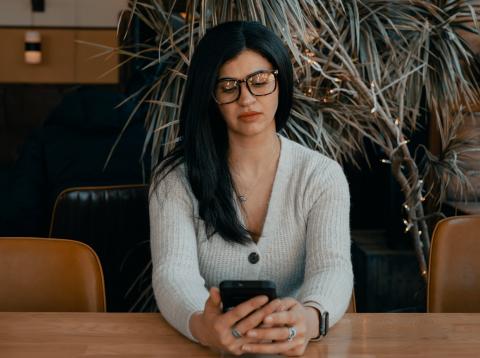 Woman sitting at table reading her mobile phone