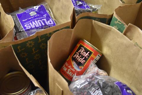 [IMAGE DESCRIPTION: Brown paper grocery bags are filled with cans and fresh food.]