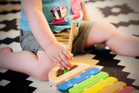 Toddler child sitting on carpet playing with toys. 