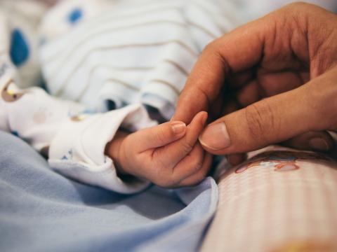 A mom grasping a baby's hand. 