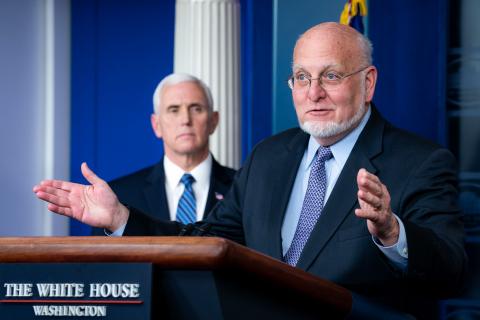 CDC Director Redfield speaks from a White House podium as VP Pence looks at him