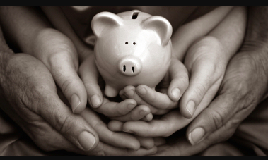 A black and white shot of a ceramic piggy bank in the hands of a young person, whose hands are held by an older set of hands.