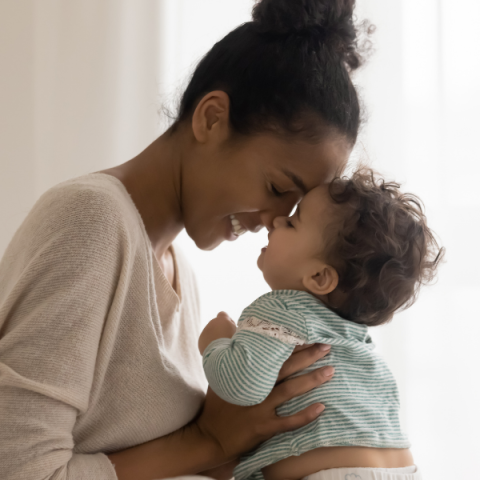 smiling mom holds her baby, forehead to forehead