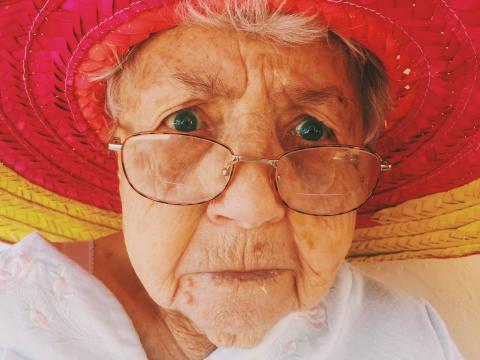 Grandmother with colorful hat staring into camera