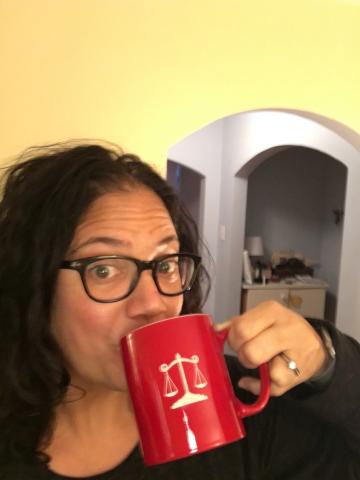 A woman drinking from a large red coffee mug