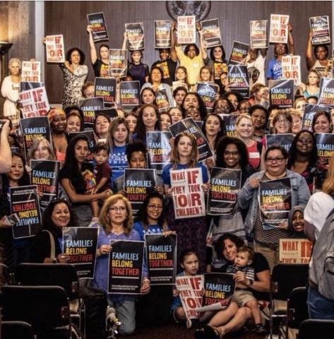 Photo of a crowd holding "Families Belong Together" signs.