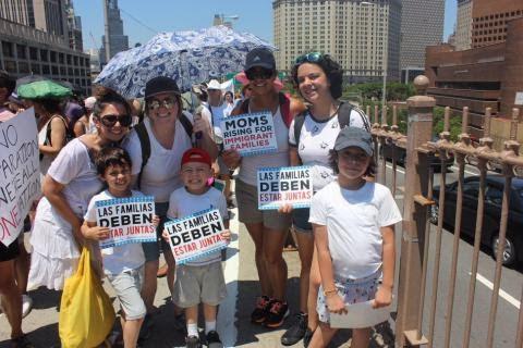 [IMAGE DESCRIPTION: A photograph of a smiling group holding signs in support of immigrant rights.]