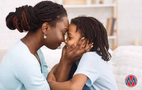 a mom holds her child's face while they smile at each other