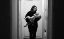 Woman in dark hallway holding toddler drinking from a bottle. 