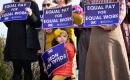 My daughter, gazing off into the distance, holding a sign demanding "Equal Pay Now" upside down.
