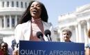 A woman speaking at a podium in front of the capitol