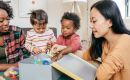 Two children and two adults playing with toys in a box