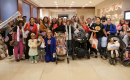 Large group of moms and kids at holding oversized "receipts" to protest affordability crisis