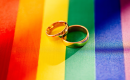 Two wedding bands sitting on top of a gay pride flag