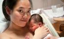 A mom with brown eyes and black hair hold her newborn baby