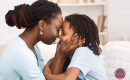 a mom holds her child's face while they smile at each other