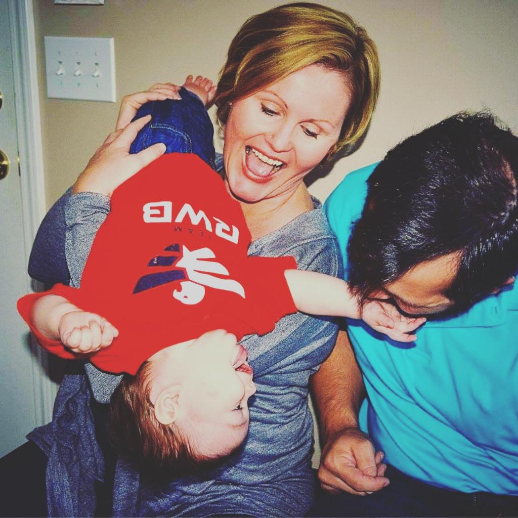Two white parents playing with a baby