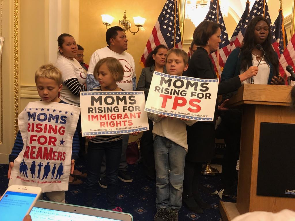 Three children hold signs in support of immigrant rights inside the U.S. Capitol.