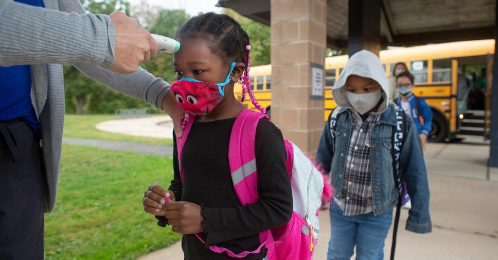 A child gets their temperature checked on the way to school