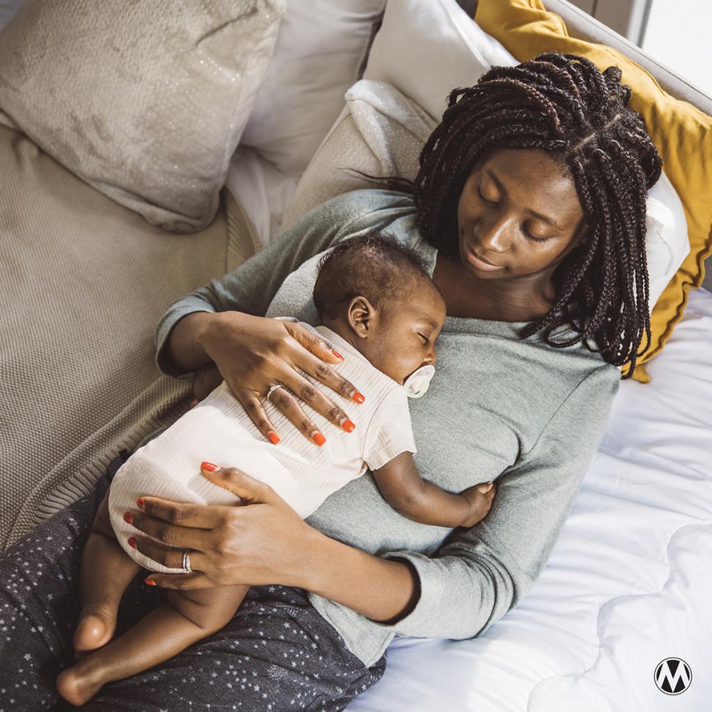 Close-up of a Black mother and sleeping baby, capturing a quiet moment of intimacy and joy.