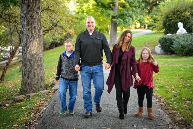 [IMAGE DESCRIPTION: A photo of a family with a dad, two tween kids, and a mom walking hand in hand outdoors.]