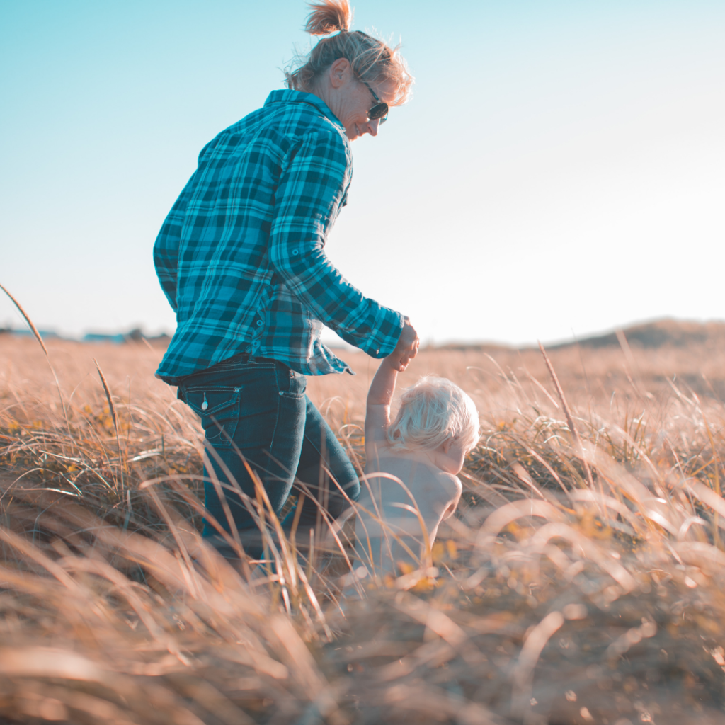 Parent holding child's hand in field