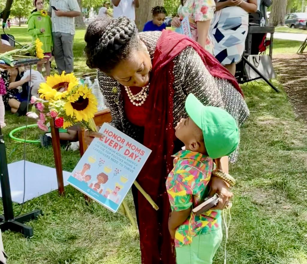 A baby Riser gives a MomsRising storybook to Rep. Sheila Jackson Lee