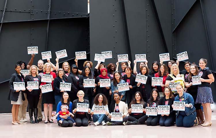 [IMAGE DESCRIPTION: A group of people holding MomsRising signs in front of the black metal sculpture inside the US Senate.]