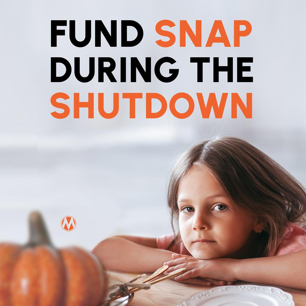 Young girl looking at the camera. There is a pumpkin and an empty plate in front of her on the table. Text reads: Fund SNAP during the shutdown.
