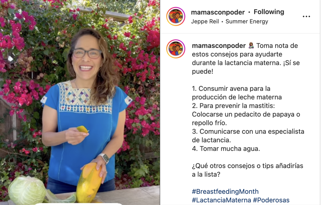 Woman against backdrop of pink flowers wearing a blue blouse and glasses, holding a papaya.