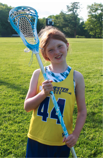 Photo of a smiling white girl with red hair holding a lacrosse stick