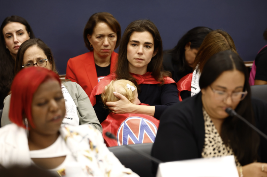 MomsRising member Nathalie holding her baby during MomsRising/DWC/Mamás Caucus "Moms Pay the Price"