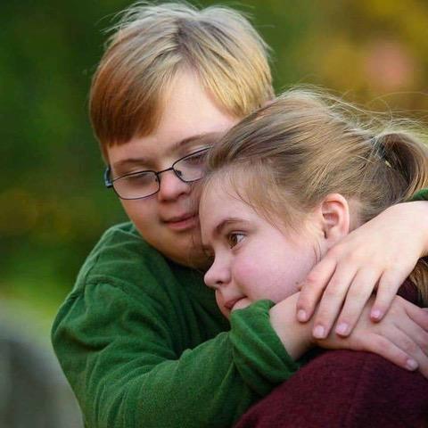  A photo of a young teen brother and sister hugging.]