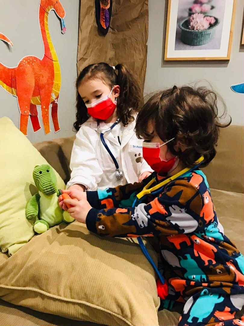 My children, using doctor kit toys to give a stuffed dinosaur toy a shot.