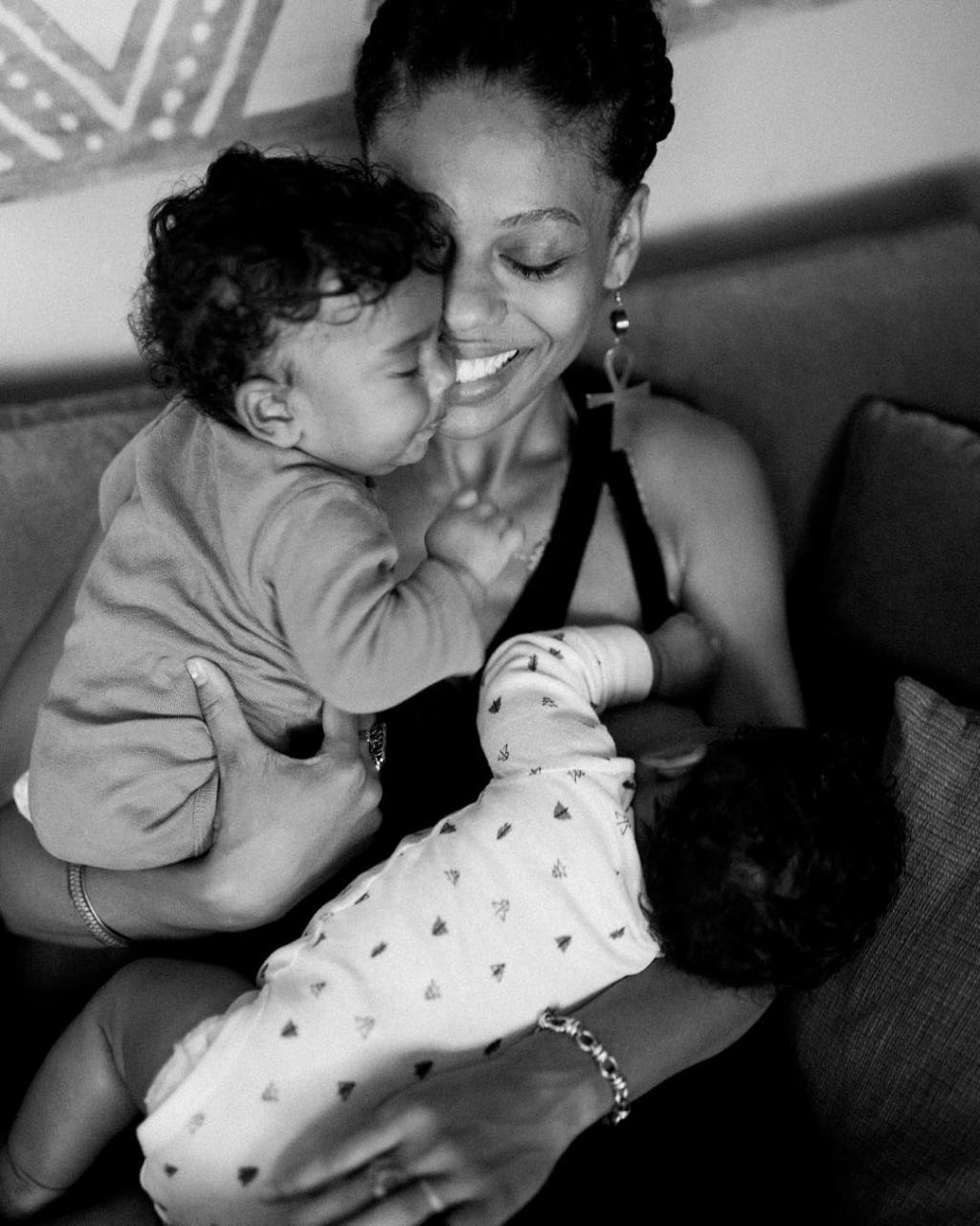 An African-American mother holding a child while breastfeeding another