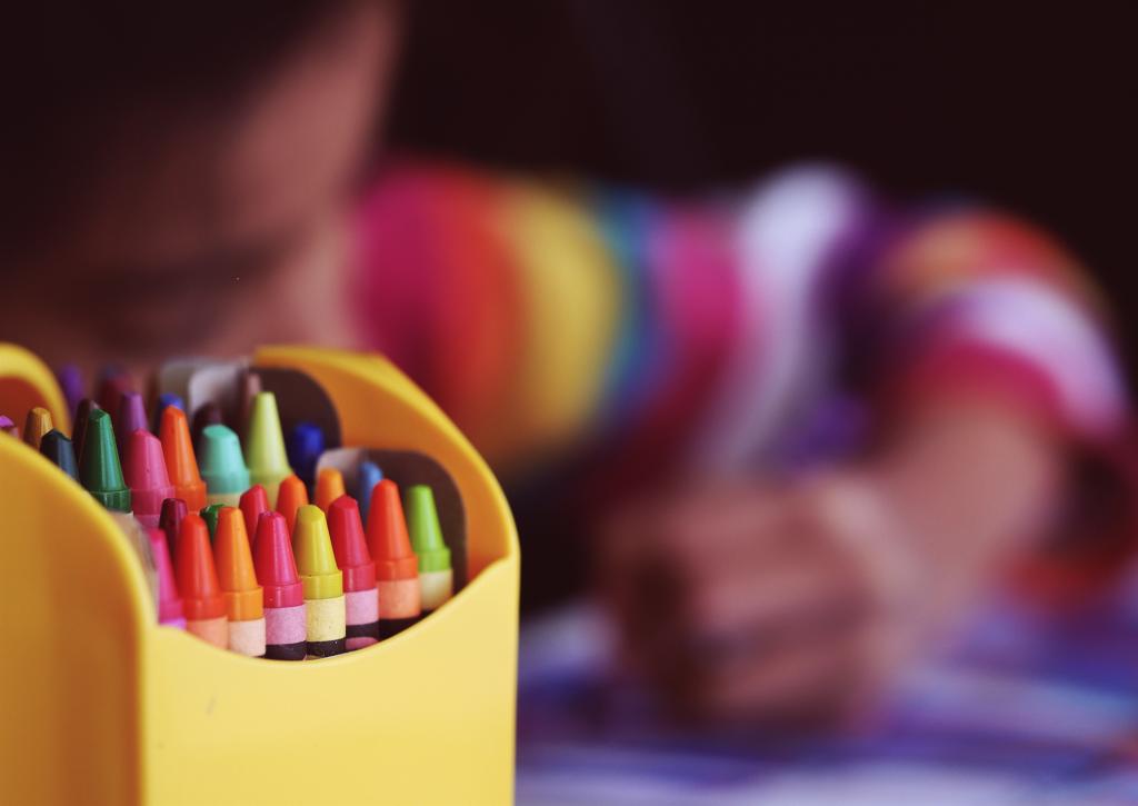 photo of child coloring with crayons in the foreground